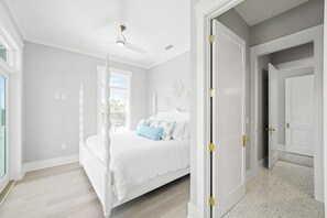 A bedroom with a bed, a ceiling fan, a window, and a door. - CSB~Ovation~5 BR Luxury Home~Beach, Bay, Pools Access~Panoramic Gulf & Bay Views (Port St. Joe)