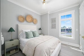 A bedroom with a bed, nightstands, wall decor, and a window with a view. - CSB~Ovation~5 BR Luxury Home~Beach, Bay, Pools Access~Panoramic Gulf & Bay Views (Port St. Joe)