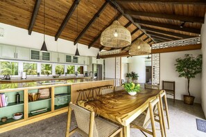 A spacious kitchen with high ceilings and exposed beams, a central island with stools, and a dining area with a wooden table and chairs. - 4br w/Incredible views of St. John and the BVI - sleeps 10 (St. Thomas)