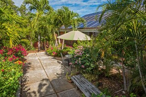 A patio with a concrete floor, surrounded by lush greenery and flowering plants. - 4br w/Incredible views of St. John and the BVI - sleeps 10 (St. Thomas)