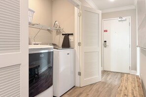 A laundry area with a washing machine, dryer, and ironing station. - Phoenix OB II #801 -- Luxury 4BR Beachfront Corner Unit, VIEWS, Lazy  River (Orange Beach)