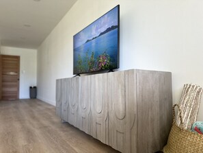 Ein modernes Wohnzimmer mit einem Holzkonsolentisch, einem Flachbildfernseher und einem gewebten Korb.