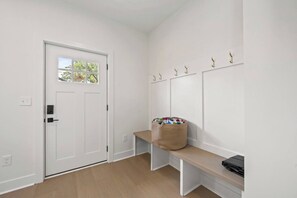 A hallway with a white door, a bench, a basket, and a coat rack. - Emerald Oasis | Hot Tub | Game Room | Sleeps 12 (Columbus)