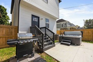 A residential backyard with a barbecue grill, a hot tub, and a wooden fence. - Emerald Oasis | Hot Tub | Game Room | Sleeps 12 (Columbus)