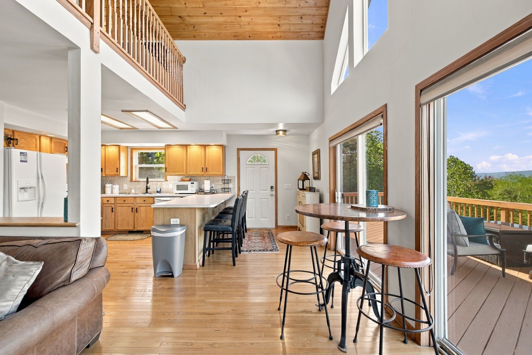 A spacious kitchen with wooden cabinets, a dining area with bar stools, and a view of the outdoors through large windows.