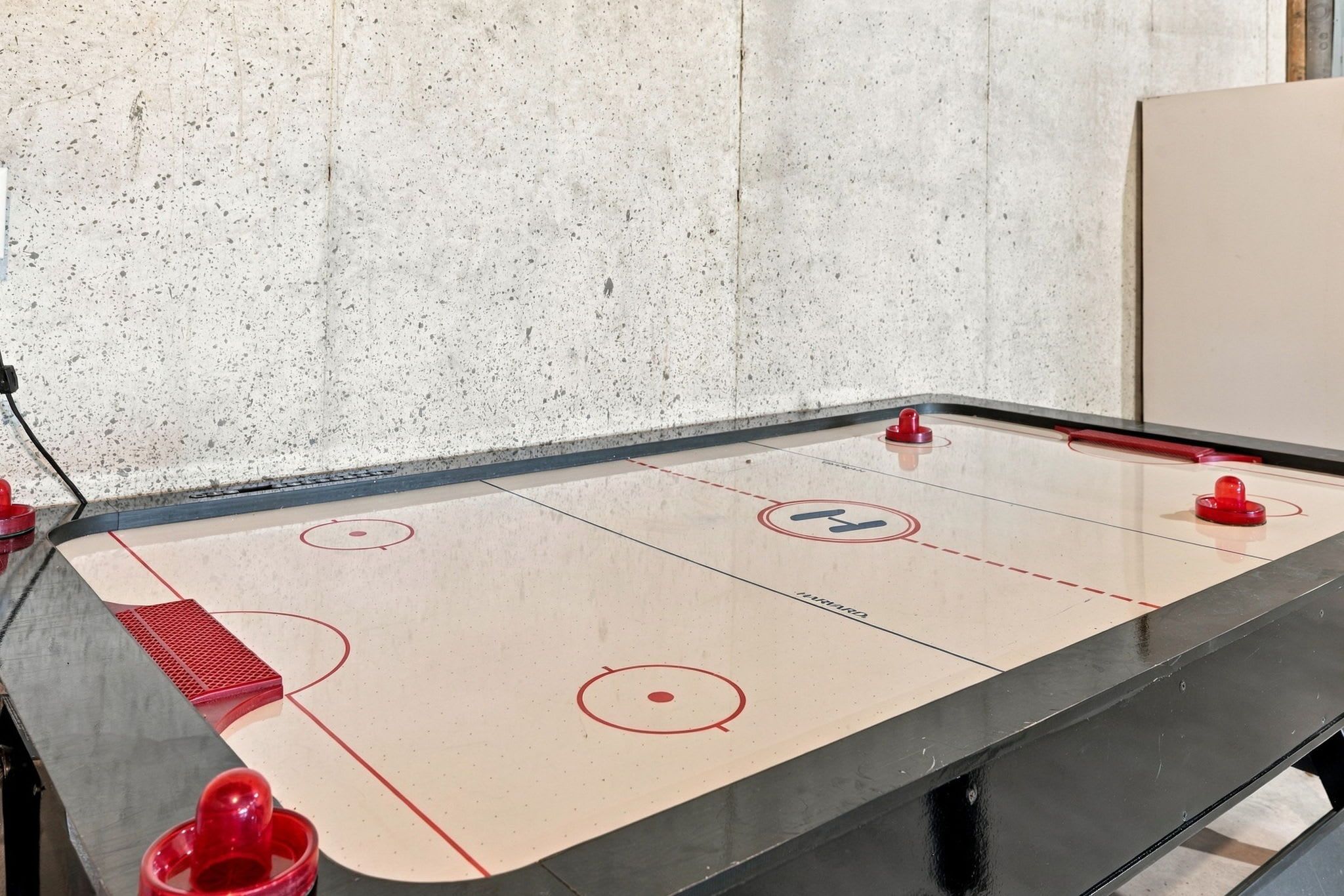 Een tafelhockeyspel met vier rode schijven en een zwarte tafel.