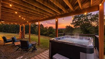 A wooden deck with a hot tub, outdoor seating, and string lights.