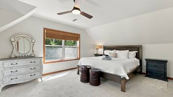 Une chambre à coucher comprenant un lit, une commode, une table de chevet et un ventilateur de plafond.
