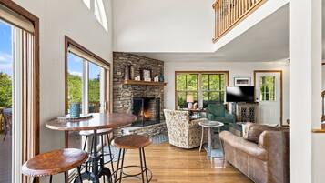 A spacious living area with a stone fireplace, a television, and a leather sofa.