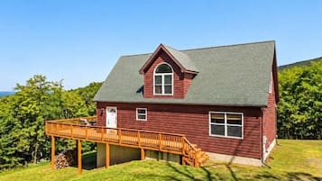 A red wooden house with a covered porch and a large window.