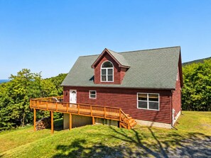 A red wooden house with a covered porch and a large window.