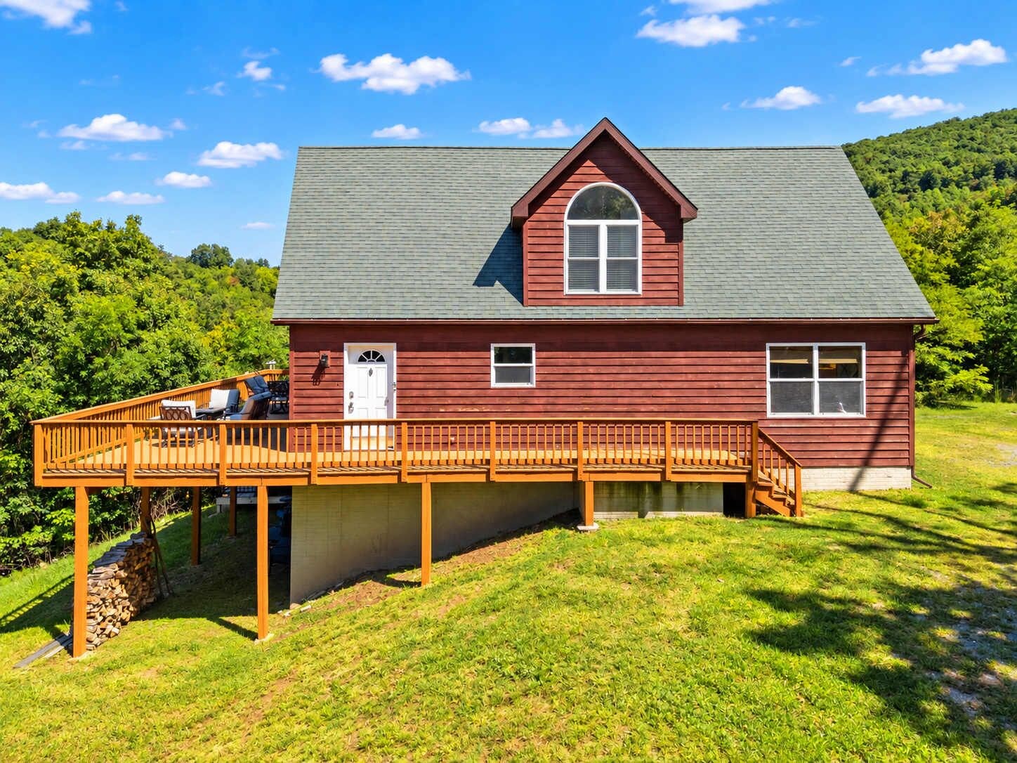 A red wooden house with a porch and a small deck.