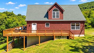 A red wooden house with a porch and a small deck.