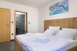 A hotel room with a wooden headboard, a bed with white linens, and a painting of dolphins on the wall. - Villa Azur – Modern Villa with a Swimming Pool and Jacuzzi on the Island of Krk (Hlapa (Krk))