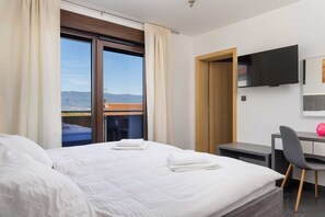 A hotel room with a bed, a desk, a chair, a TV, and a view of the city. - Villa Azur – Modern Villa with a Swimming Pool and Jacuzzi on the Island of Krk (Hlapa (Krk))