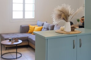A living room with a sofa, a coffee table, and a cabinet with a vase of dried plants. - Spacious apartment in Naxos Town – 300m from Beach. Ideal for families & friends (naxos town)