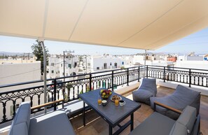 A balcony with a table, chairs, and a view of the cityscape. - Spacious apartment in Naxos Town – 300m from Beach. Ideal for families & friends (naxos town)