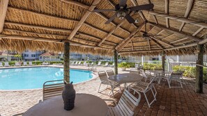 A poolside area with a thatched roof, lounge chairs, and a table. - 3BR/3BA condo, close to South Beach (Marco Island)