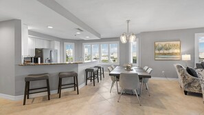 Una cocina moderna con una isla central, taburetes de bar y una zona de comedor con mesa y sillas.