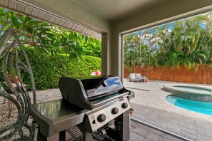 An outdoor patio with a grill, a pool, and a view of tropical vegetation. - Your Peaceful Island Getaway - 3 BR/3 Bath (Marco Island)