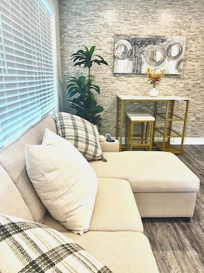 A modern living room with a sectional sofa, a small table, and a decorative wall piece.