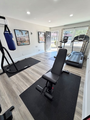 A gym with exercise equipment, a bench, and a treadmill. - NoDa Cottage Near Uptown (Charlotte)