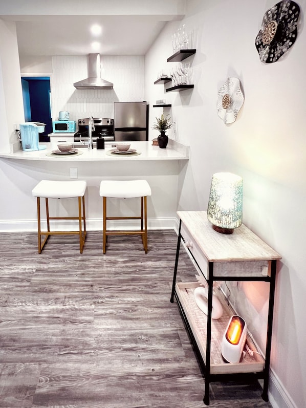 A modern kitchen with a central island, bar stools, and a decorative table with a light.