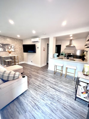 A modern living room with a sofa, a coffee table, and a TV mounted on the wall.