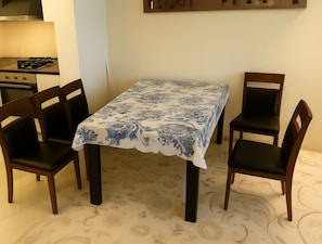 Ein Essbereich mit einem Tisch, der mit einer blumigen Tischdecke bedeckt ist, umgeben von vier Stühlen.