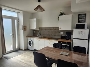 A compact kitchen with a washing machine, a microwave, and a refrigerator.