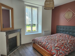 A bedroom with a bed, a window, a fireplace, and a wall decoration.