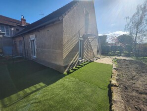 A residential property with a concrete exterior, a staircase leading to a door, and a well-maintained lawn.