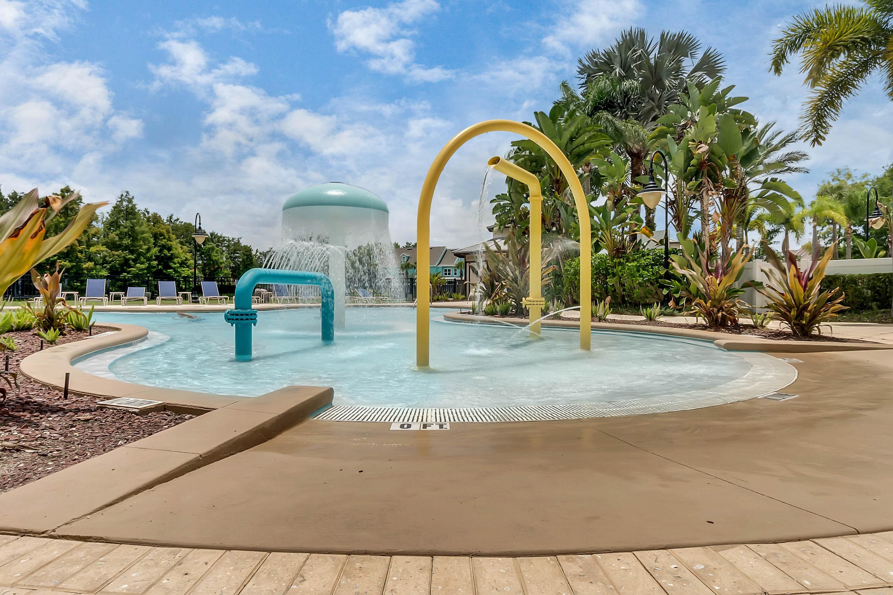 A pool area with a water feature, lounge chairs, and tropical plants.