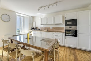 Una cocina moderna con armarios blancos, una mesa de comedor de madera y un microondas empotrado.