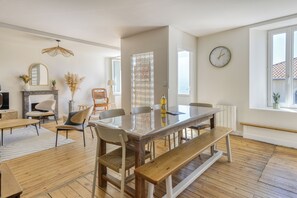 Un salón amplio con suelo de madera, una mesa de comedor con bancos, un sofá, un televisor y una chimenea.