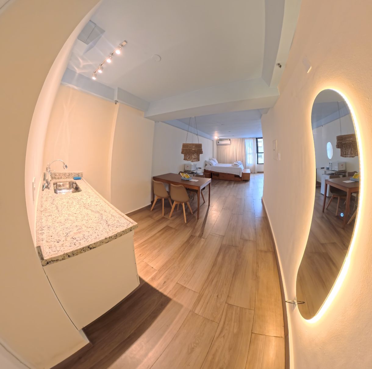 Une chambre d’hôtel moderne dotée d’un coin cuisine, d’une table à manger et d’un grand lit.