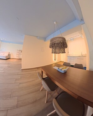 A modern dining area with a wooden table, chairs, and a unique hanging light fixture. - Carió, studio apartment in Copacabana, a few steps from the beach and Leme. (Rio de Janeiro)