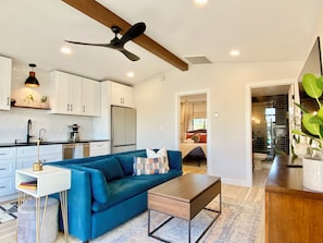 A modern kitchen with white cabinets, a black countertop, and a ceiling fan.