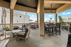 An outdoor patio area with tables and chairs, a ceiling fan, and a view of buildings in the background.