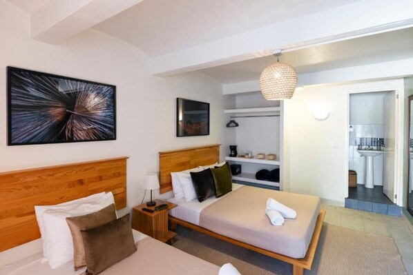 A hotel room with a wooden headboard, a bed with white linens, a bedside table with a lamp, a wall-mounted artwork, and a hanging light fixture. - Origen by ÓOL Hotels (Oaxaca)