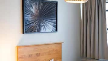 Ein Hotelzimmer mit einem Bett, einem Nachttisch mit Lampe, einem Wandbild und einer Pendelleuchte.