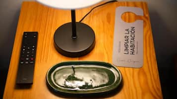 Mesa de madeira com controle remoto, luminária e placa.