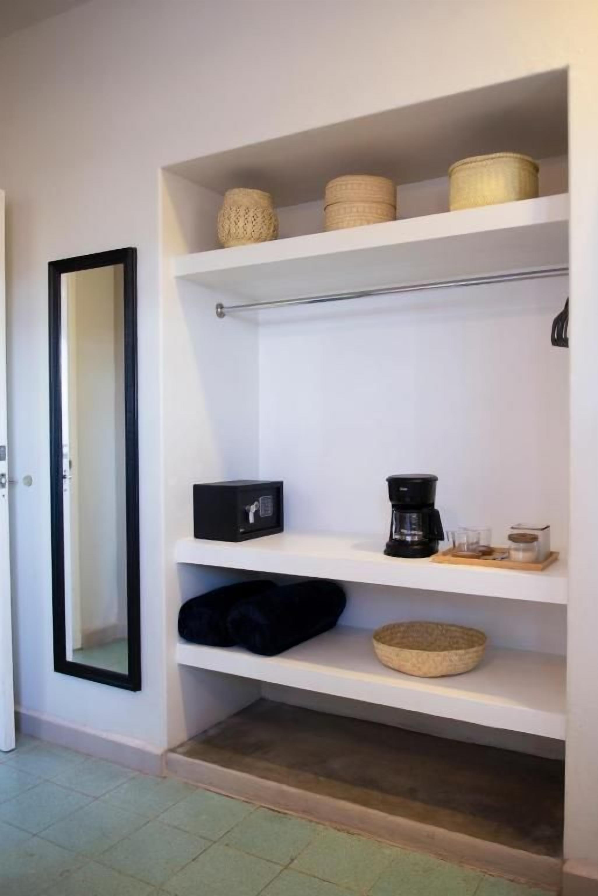 A white shelf unit with baskets, a coffee maker, and a bowl.