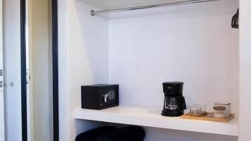 A white shelf unit with baskets, a coffee maker, and a bowl.