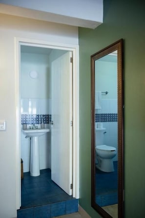 A bathroom with a white sink, a toilet, and a mirror. - Origen by ÓOL Hotels (Oaxaca)