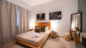 Quarto de hotel com cama, mesas de cabeceira, espelho e obras de arte nas paredes.