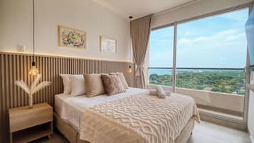 Quarto moderno com cama grande, mesa de cabeceira, vaso com pena de pluma, duas obras de arte na parede e grande janela com vista para a cidade.