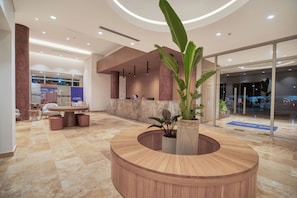 A reception area with a wooden reception desk, a seating area with chairs, and a large potted plant. - MARESIA SANTA MARTA 1209 (Santa Marta)