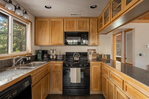 A kitchen with wooden cabinets, a stove, and a sink. - The Village Villa - Hot Tub, Walk to village (Big Bear Lake)