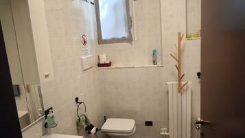 Ein Badezimmer mit Waschbecken, Bidet, Toilette und einem Fenster.